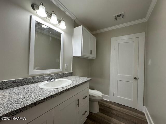 bathroom with wood-type flooring, vanity, toilet, and crown molding