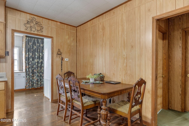 dining space with wooden walls and crown molding