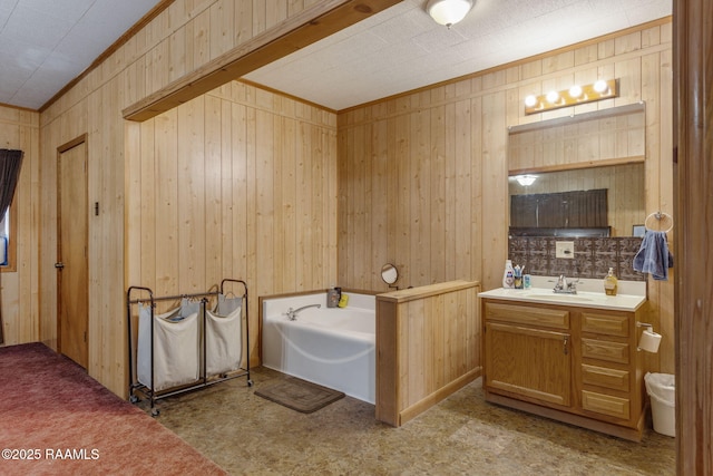 bathroom featuring ornamental molding, a washtub, wooden walls, and vanity