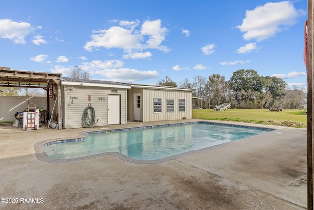 view of pool with a lawn, an outbuilding, and a patio area