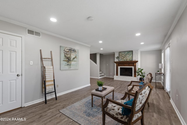 living room featuring dark hardwood / wood-style flooring, ornamental molding, and a brick fireplace