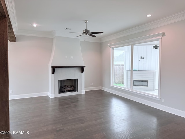 unfurnished living room featuring a large fireplace, crown molding, ceiling fan, and dark wood-type flooring