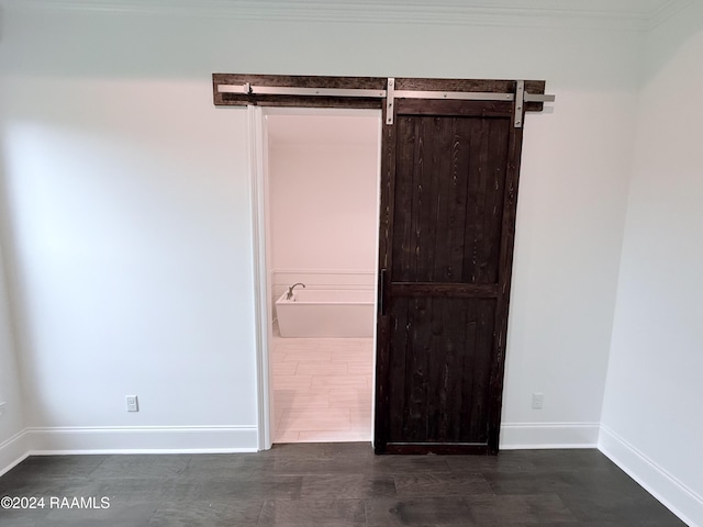 spare room featuring a barn door and dark wood-type flooring