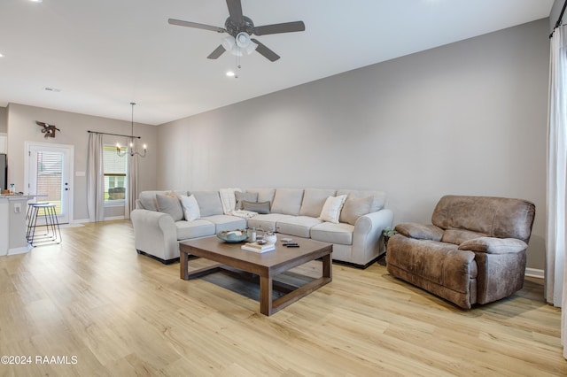 living room featuring ceiling fan with notable chandelier and light wood-type flooring