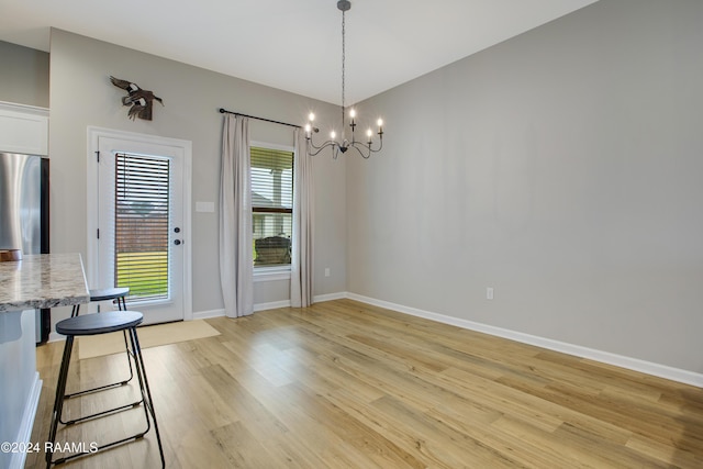 unfurnished dining area with light hardwood / wood-style floors, a wealth of natural light, and a chandelier