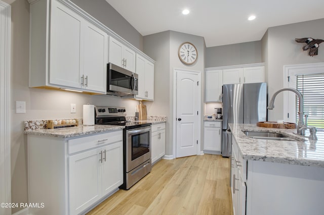 kitchen featuring sink, white cabinets, stainless steel appliances, and light wood-type flooring