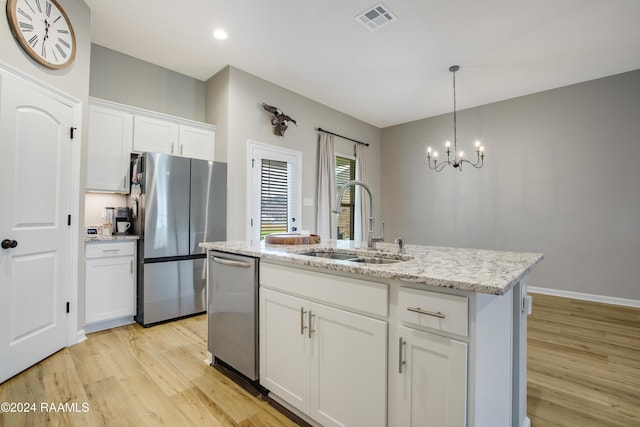 kitchen with appliances with stainless steel finishes, sink, light hardwood / wood-style flooring, white cabinets, and an island with sink