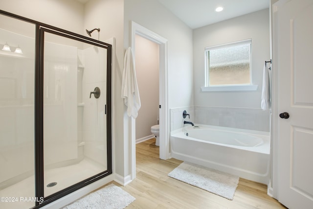 bathroom featuring wood-type flooring, shower with separate bathtub, and toilet