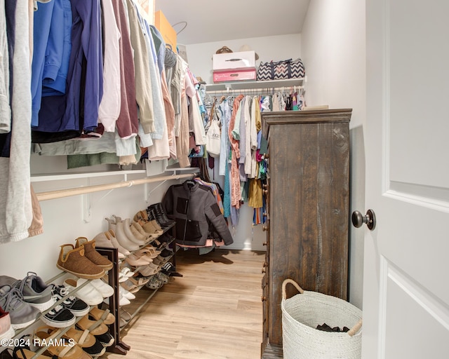 walk in closet with light hardwood / wood-style flooring