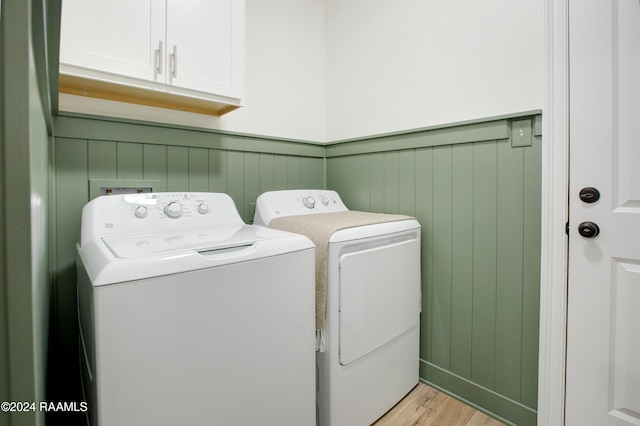 laundry area with cabinets, light hardwood / wood-style floors, and washing machine and clothes dryer