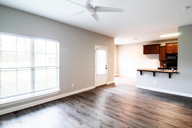 unfurnished living room with ceiling fan, sink, and dark hardwood / wood-style floors