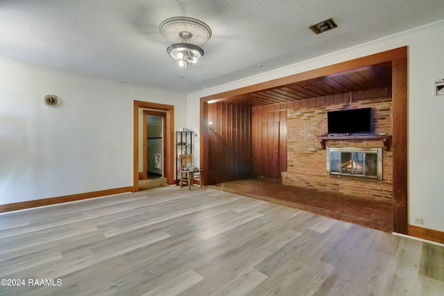 unfurnished living room featuring a fireplace, visible vents, wood finished floors, and baseboards