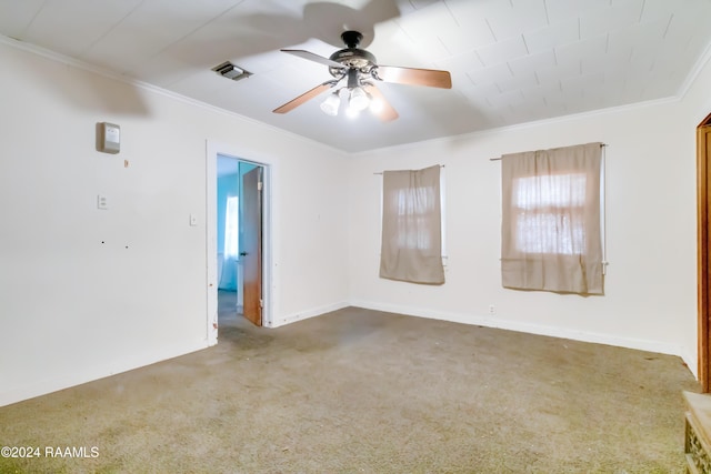 carpeted empty room with visible vents, baseboards, ceiling fan, and crown molding