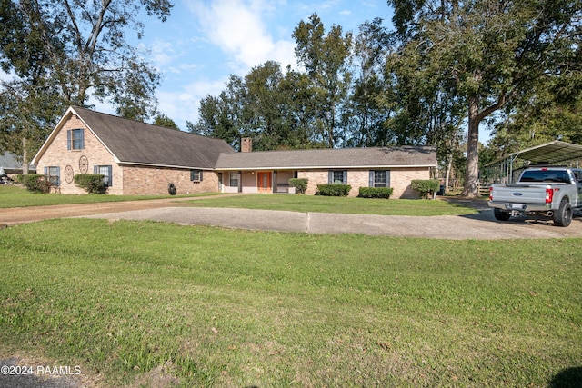 view of front of property with brick siding, a chimney, a carport, driveway, and a front lawn