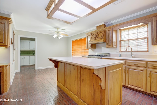 kitchen featuring sink, crown molding, ceiling fan, a kitchen island, and stainless steel range oven