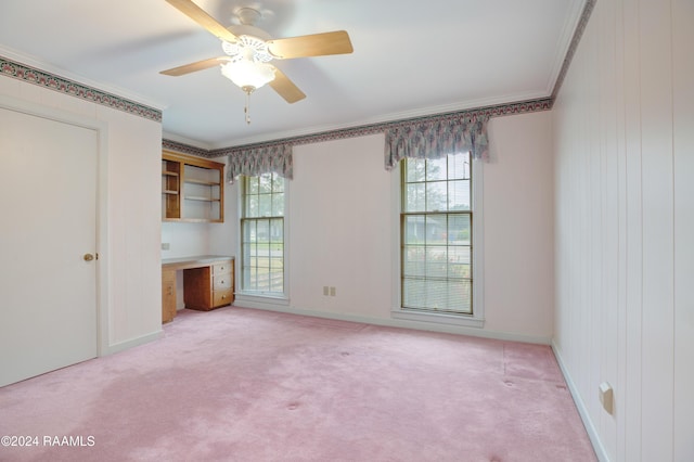 unfurnished bedroom featuring ceiling fan, crown molding, built in desk, and light carpet