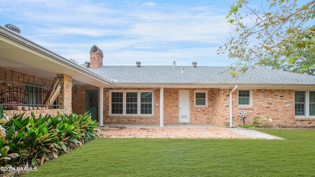 rear view of house featuring a lawn and a patio