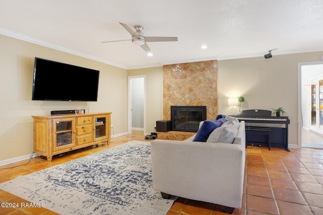 tiled living room with ceiling fan, a stone fireplace, and ornamental molding