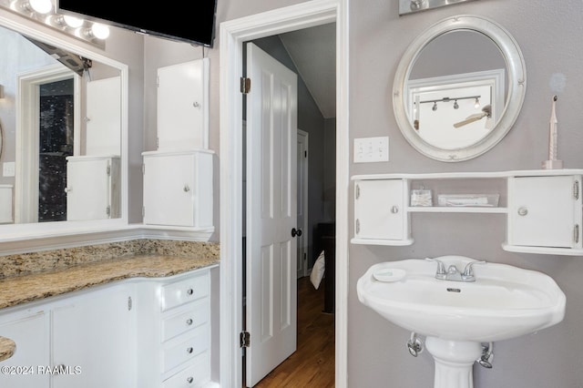 bathroom with hardwood / wood-style flooring and vaulted ceiling