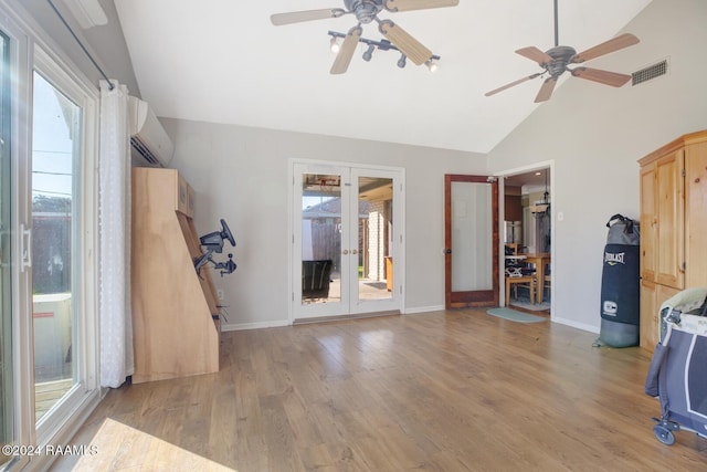 living room with a wall mounted air conditioner, french doors, light wood-type flooring, and plenty of natural light