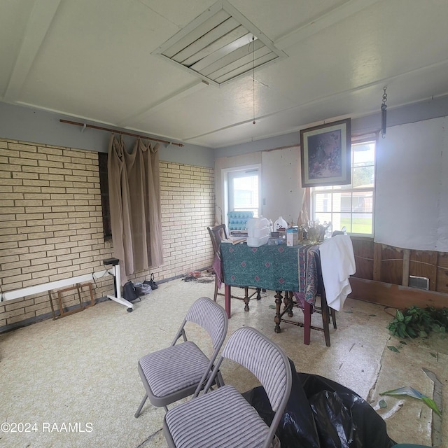 carpeted dining space with brick wall