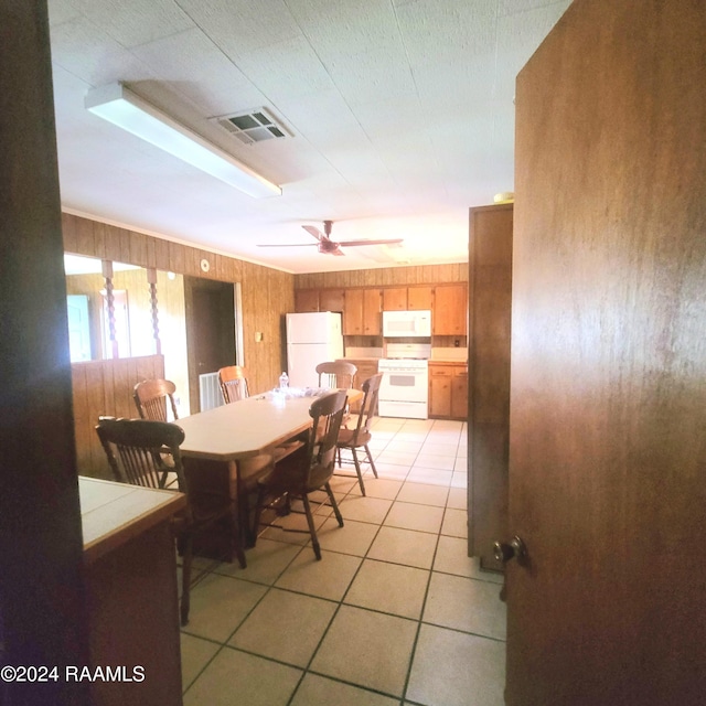 dining room featuring ceiling fan, light tile patterned flooring, and wooden walls