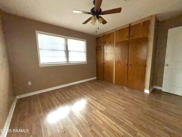 unfurnished bedroom featuring ceiling fan, hardwood / wood-style flooring, and a closet