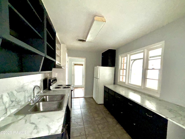 kitchen with white fridge, a healthy amount of sunlight, electric range, and sink