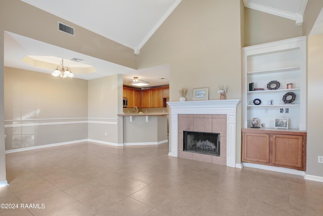 unfurnished living room with built in features, a notable chandelier, crown molding, a fireplace, and light tile patterned floors