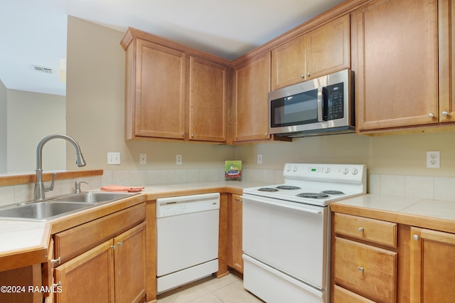 kitchen featuring sink, light tile patterned flooring, and white appliances