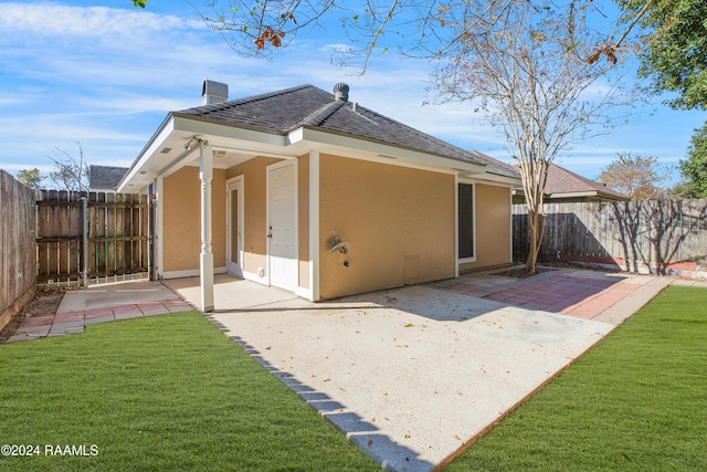 rear view of house featuring a lawn and a patio