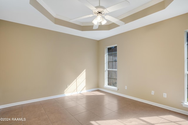 tiled spare room with a raised ceiling, ceiling fan, and crown molding