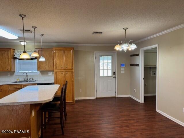 kitchen featuring crown molding, sink, dark hardwood / wood-style floors, a textured ceiling, and decorative light fixtures