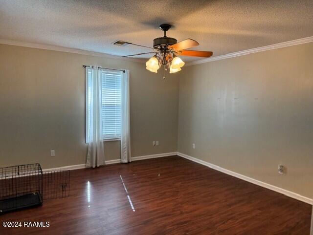 spare room featuring ornamental molding, a textured ceiling, ceiling fan, and dark wood-type flooring