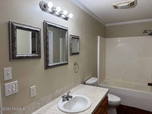 full bathroom with vanity, toilet, ornamental molding, and a textured ceiling