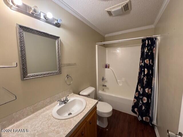 full bathroom featuring shower / bath combo with shower curtain, hardwood / wood-style floors, a textured ceiling, and ornamental molding