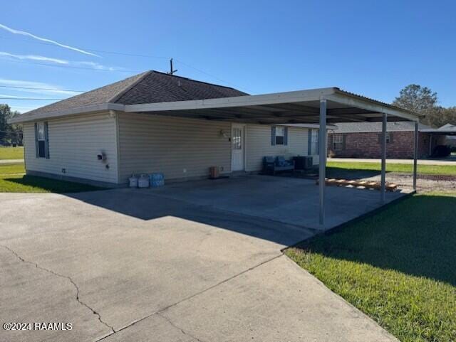 back of property with a carport and a lawn