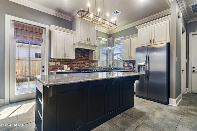 kitchen with backsplash, a wealth of natural light, stainless steel fridge, and crown molding