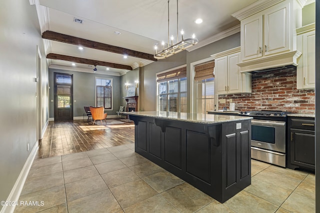 kitchen with a kitchen island, light stone counters, pendant lighting, light hardwood / wood-style floors, and stainless steel stove