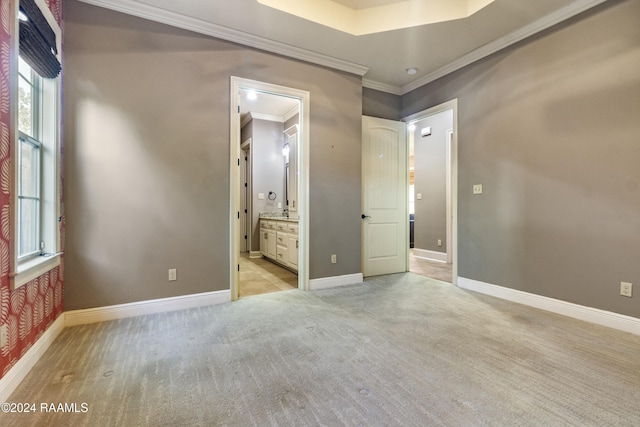 unfurnished bedroom with ensuite bathroom, crown molding, and light colored carpet