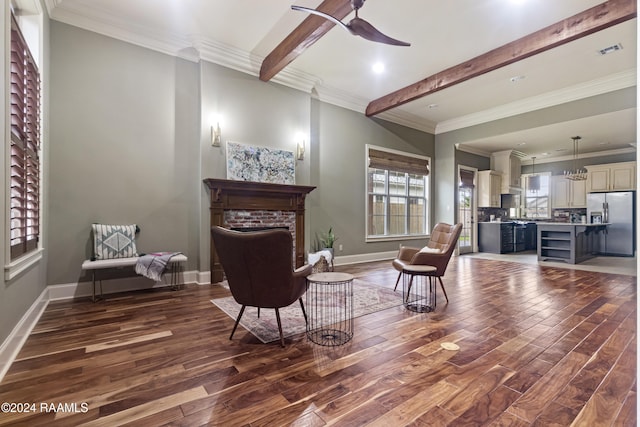 sitting room featuring a fireplace, ceiling fan, crown molding, dark wood-type flooring, and beamed ceiling