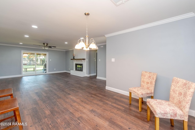 interior space with ceiling fan with notable chandelier, ornamental molding, a fireplace, and dark wood-type flooring