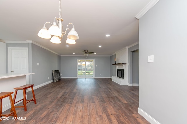 unfurnished living room featuring ornamental molding, dark wood-type flooring, ceiling fan with notable chandelier, and a brick fireplace