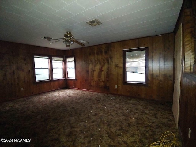 carpeted spare room featuring ceiling fan and wooden walls