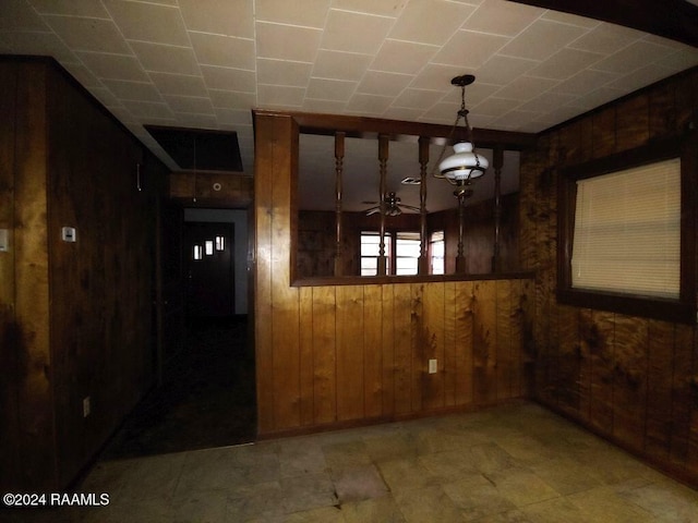 unfurnished dining area featuring wooden walls and ceiling fan