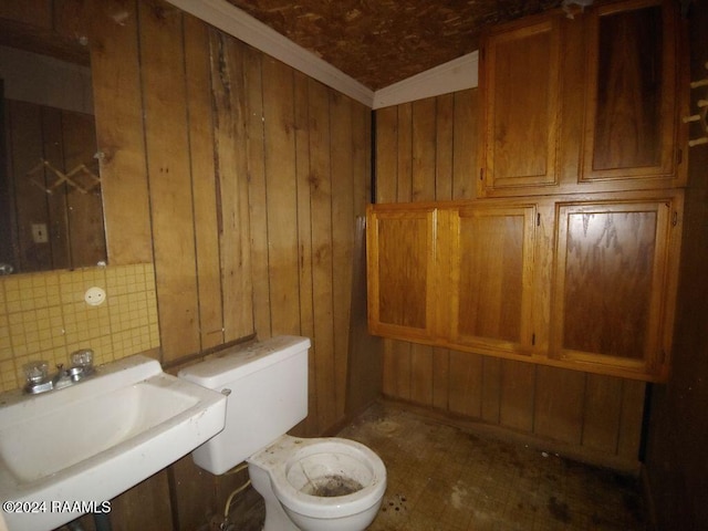 bathroom featuring decorative backsplash, wood walls, sink, and toilet