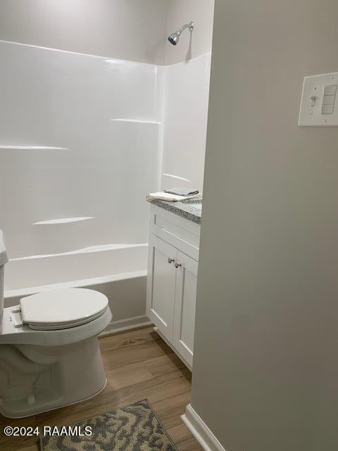 bathroom featuring bathing tub / shower combination, vanity, toilet, and wood finished floors