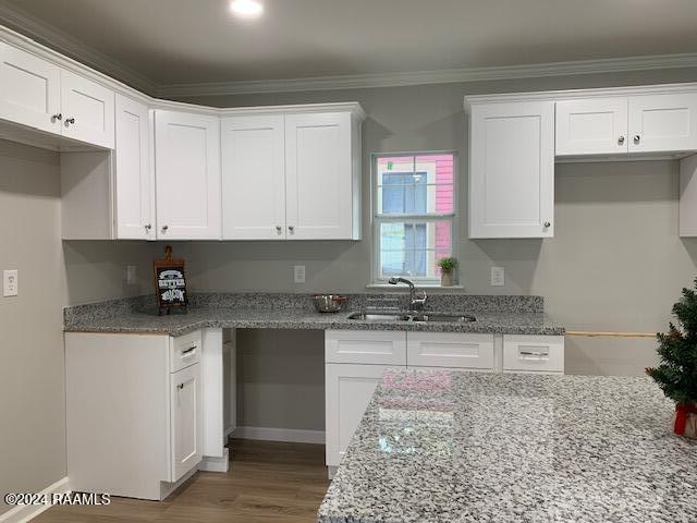 kitchen featuring light stone counters, white cabinets, and a sink