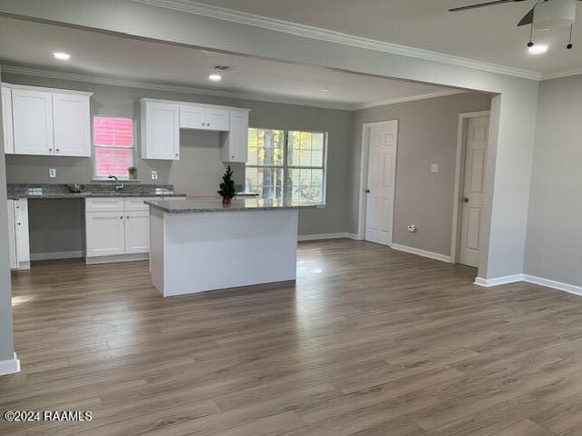 kitchen featuring white cabinetry, a kitchen island, baseboards, and wood finished floors