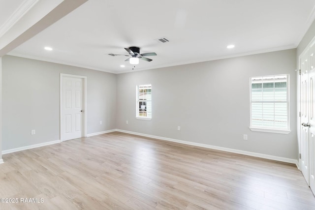 empty room with ornamental molding, light wood-type flooring, visible vents, and baseboards